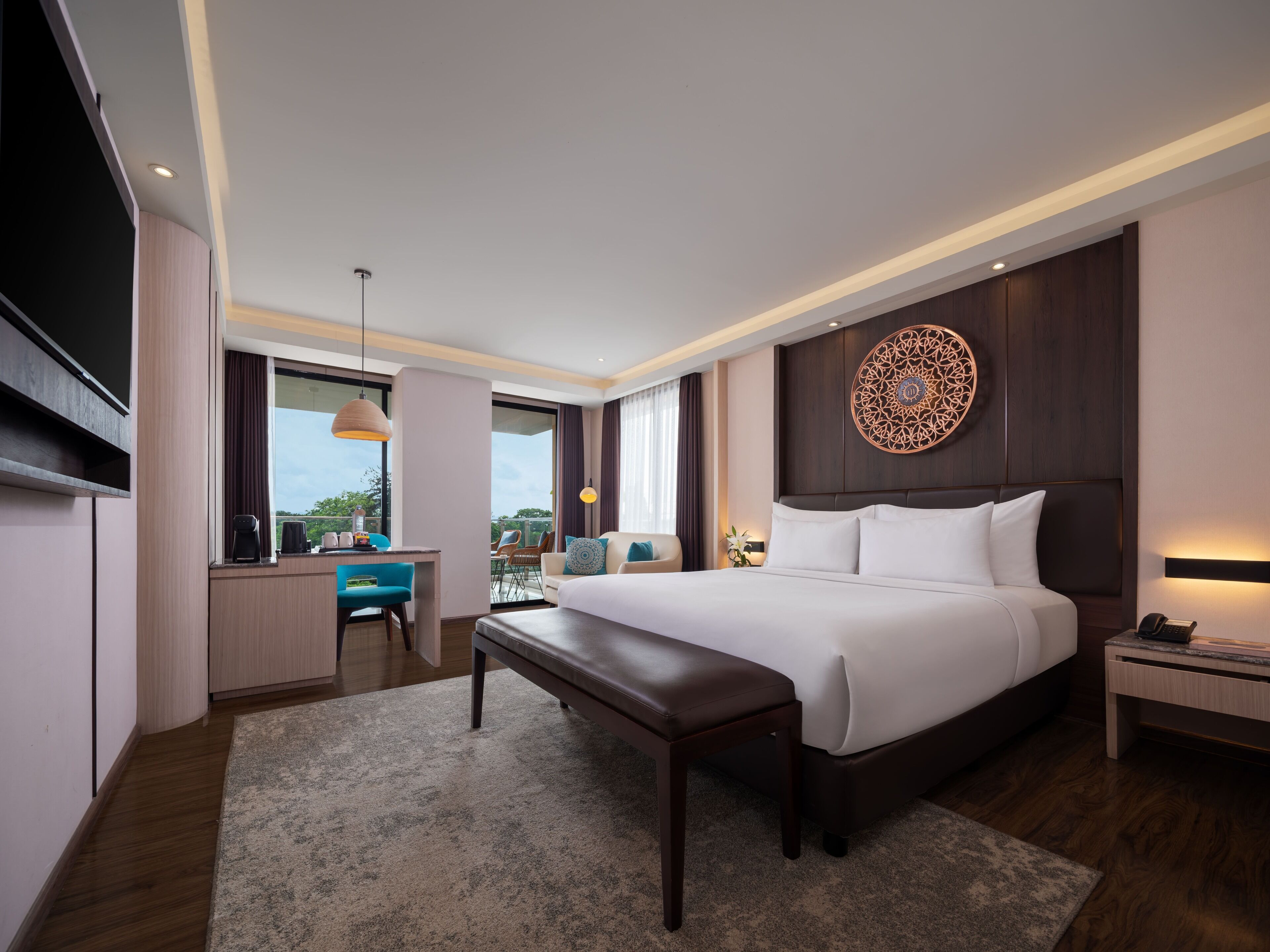 A modern hotel room with a large bed, a desk, a chair, and a TV.