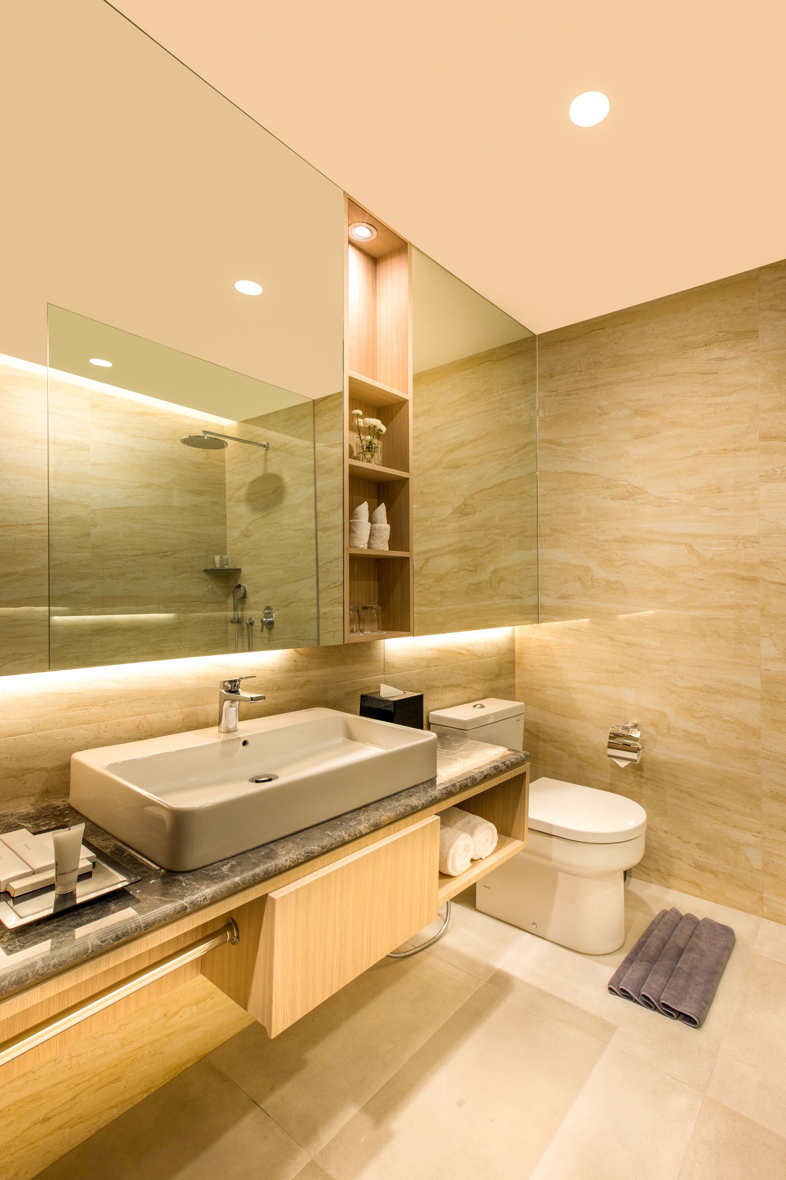Un baño moderno con un espejo grande, un lavabo, un inodoro y una ducha.