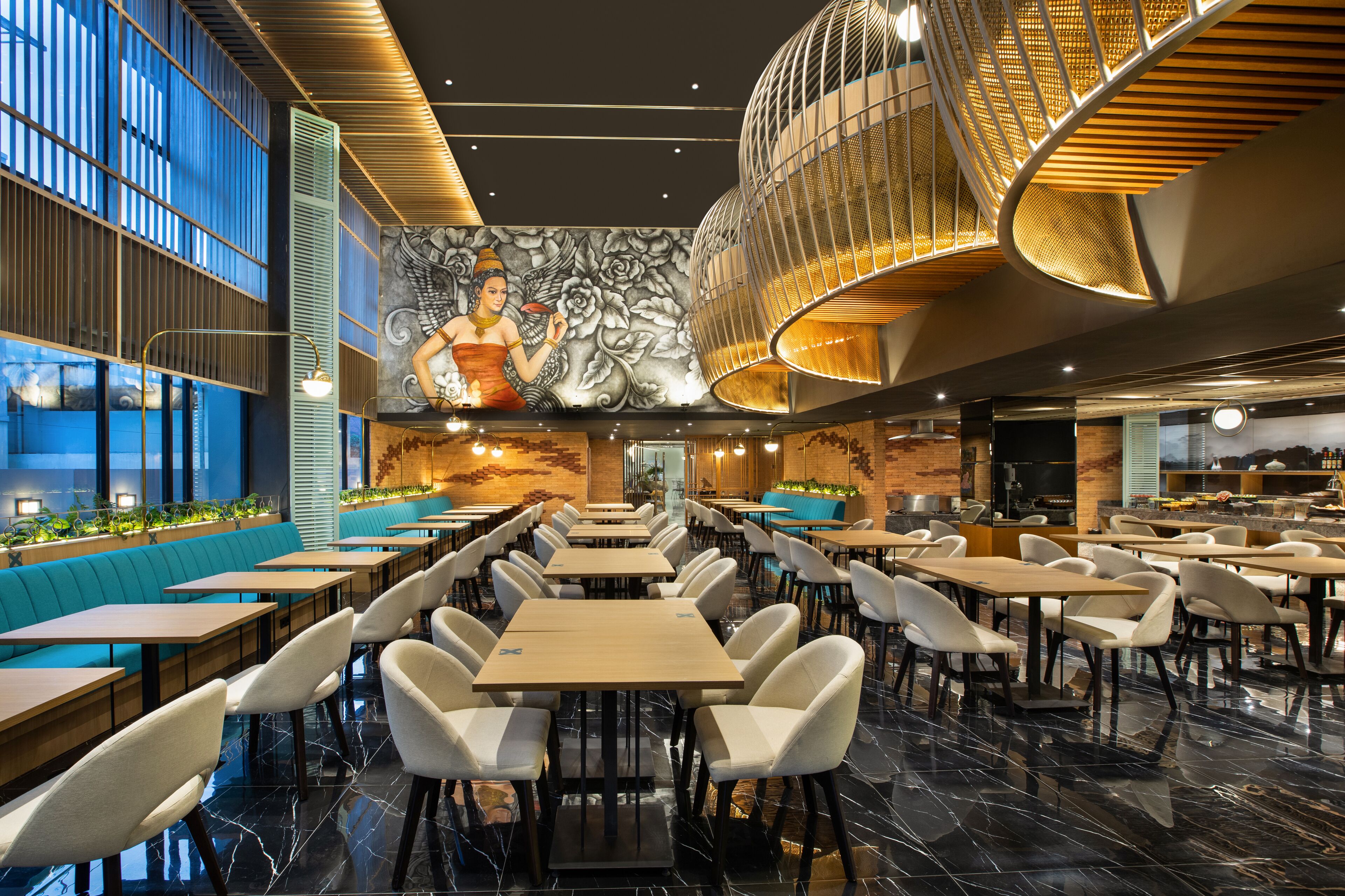 Un restaurant moderne avec de hauts plafonds, une fresque murale et différents types de sièges, notamment des banquettes et des tables.