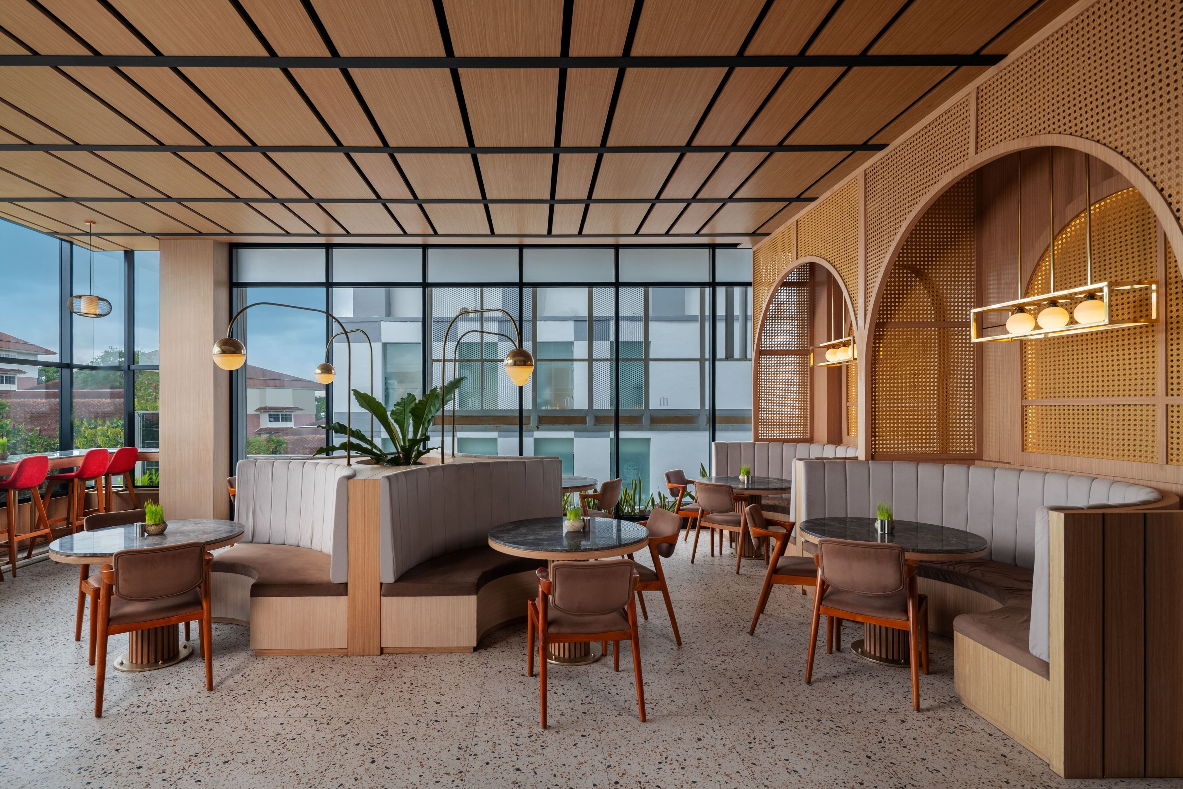 Um restaurante moderno com mesas redondas, assentos acolchoados e grandes janelas que oferecem vista da cidade.