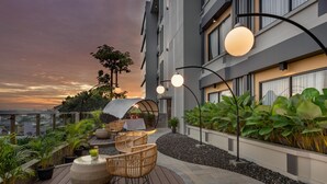 A rooftop terrace with outdoor seating, potted plants, and a sunset view. - The Manohara Hotel Yogyakarta (Depok)