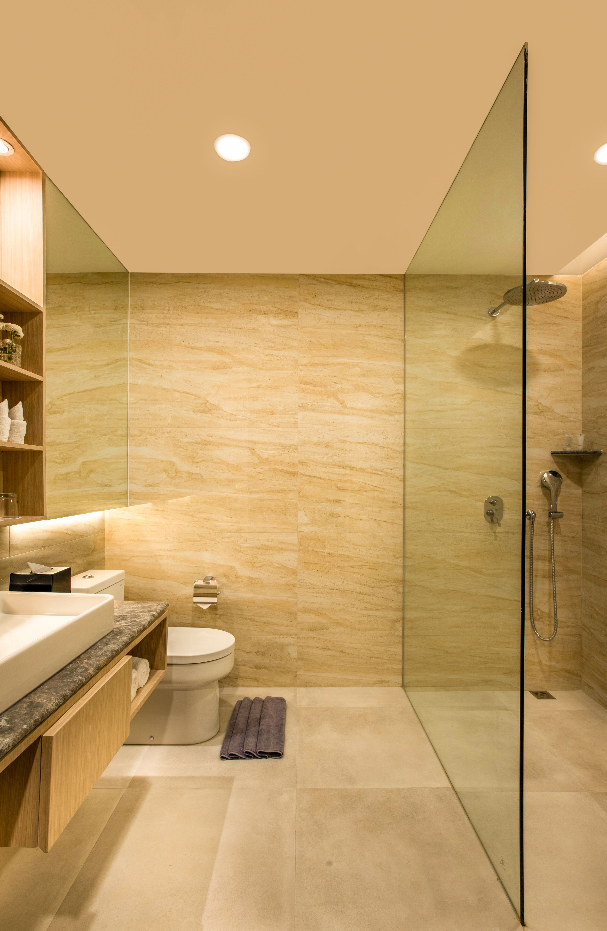 A modern bathroom with a glass shower enclosure, a wooden vanity, and a marble-tiled floor.
