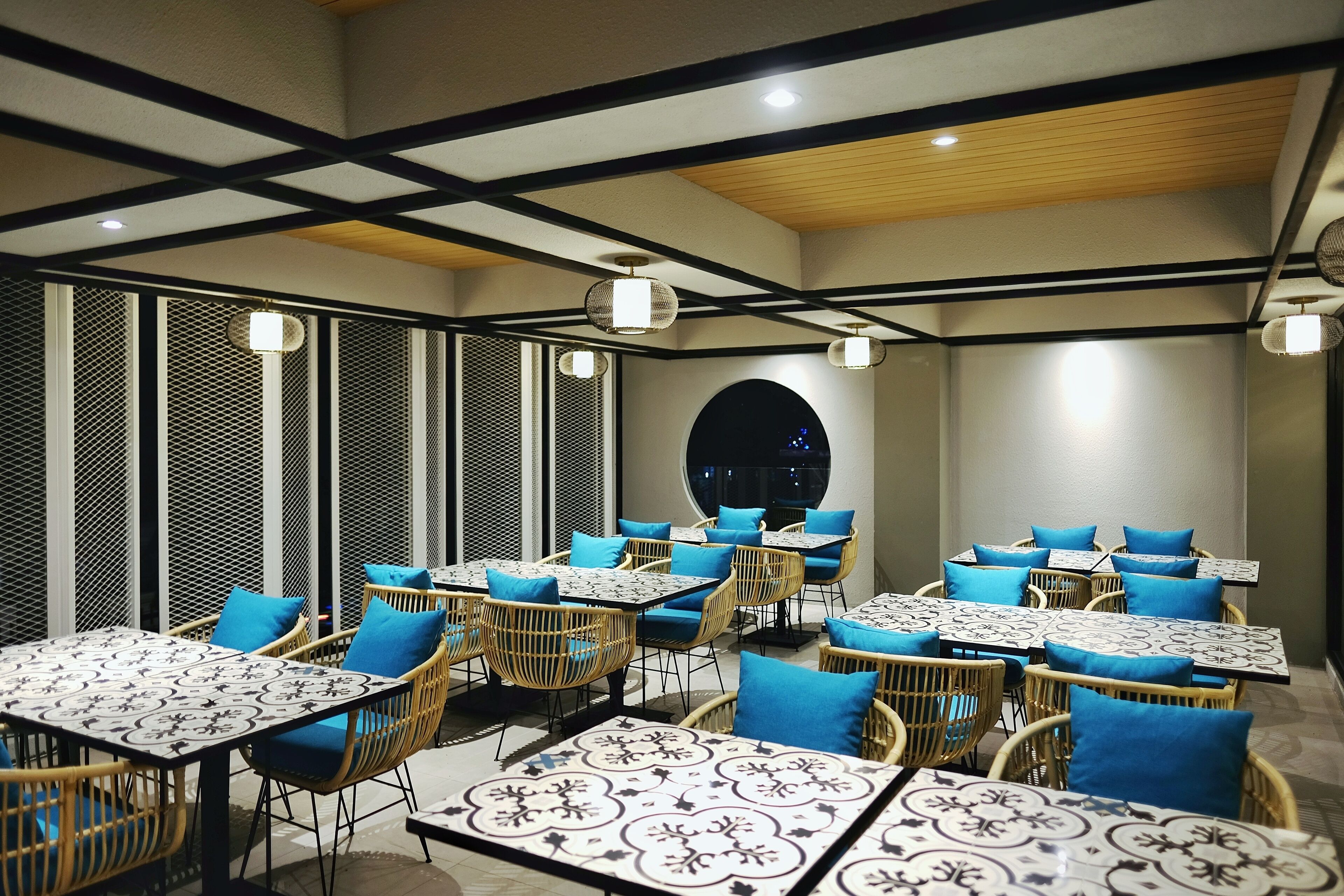 Un restaurante con mesas y sillas, un suelo con diseño y un techo de vigas de madera.