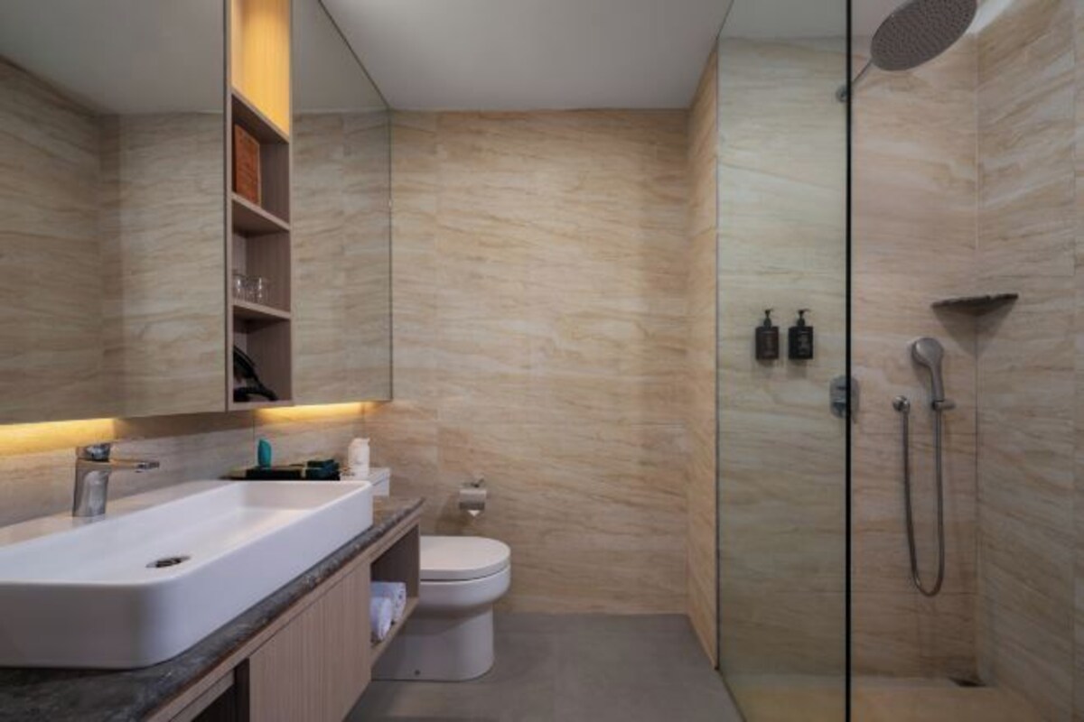 Un baño moderno con un espejo grande, un lavabo, un inodoro y una zona de ducha.
