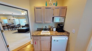 A compact kitchen with wooden cabinets, a built-in microwave, a coffee maker, and a dishwasher.