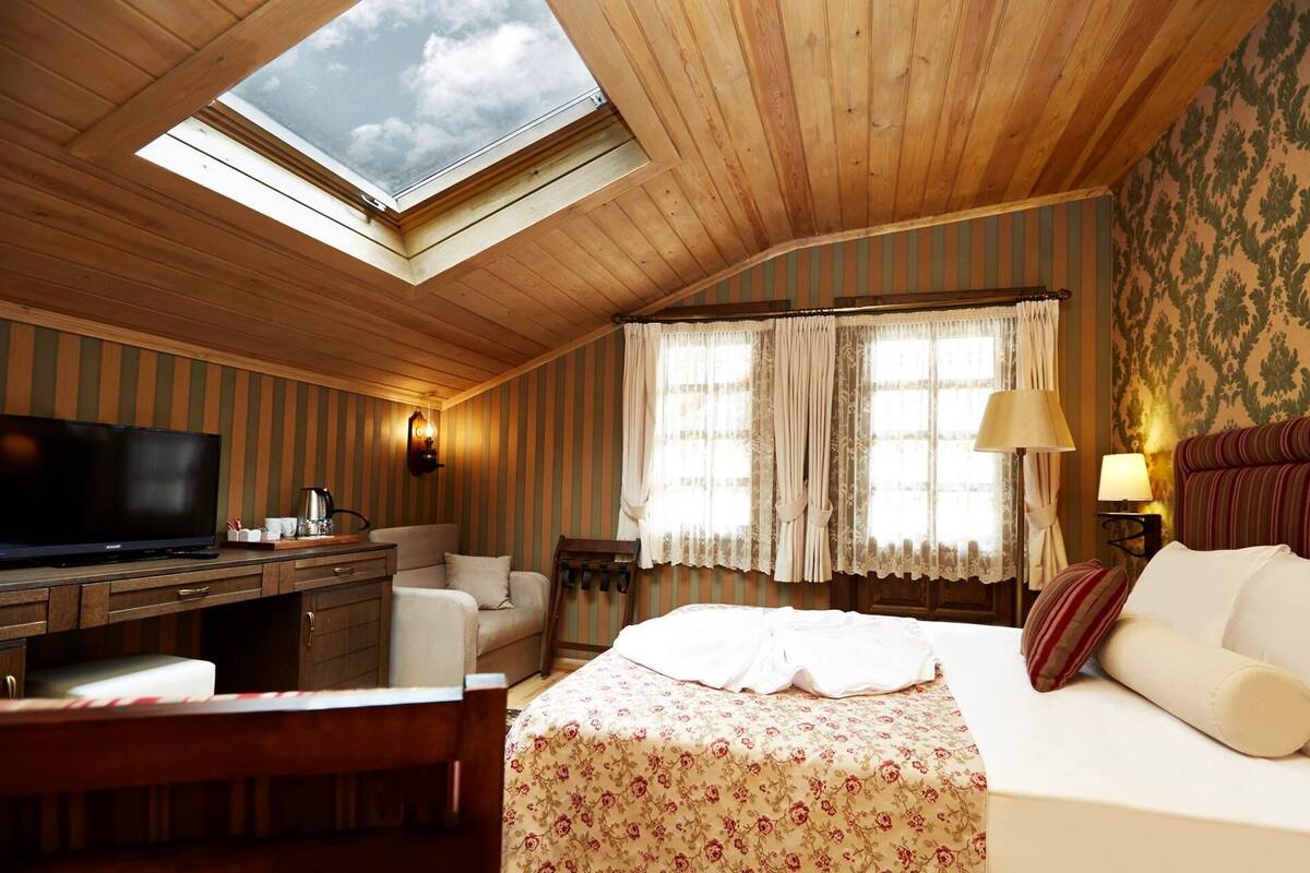 Een gezellige kamer met dakraam, een bed, een bureau en een televisie.