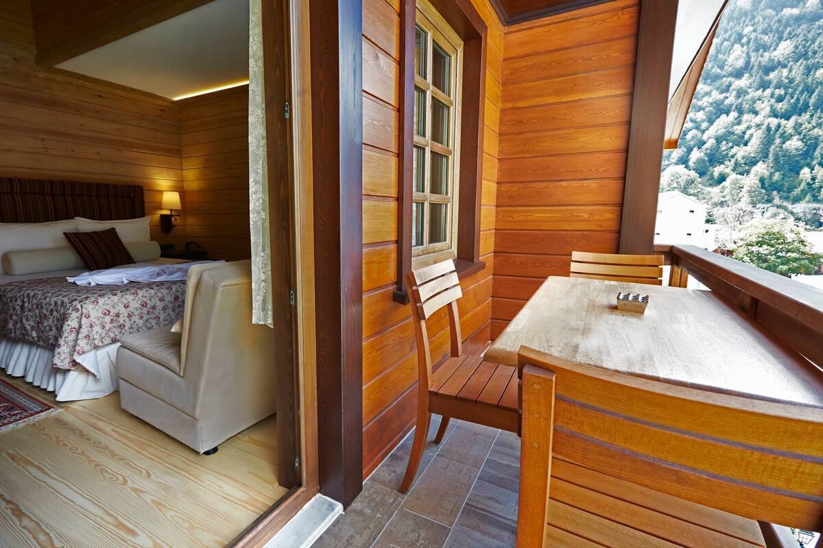 Een houten chalet met een bed, een kleine tafel en een bank.
