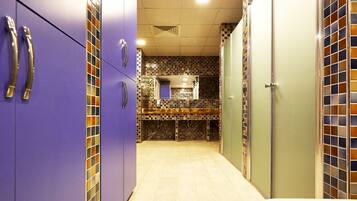 A narrow hallway with purple lockers, a tiled backsplash, and a light-colored floor.