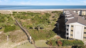 A coastal hotel with a beach view, a wooden boardwalk, and a parking area. - Lighthouse Point 6C | Pool Views, Beach Access! (Tybee Island)