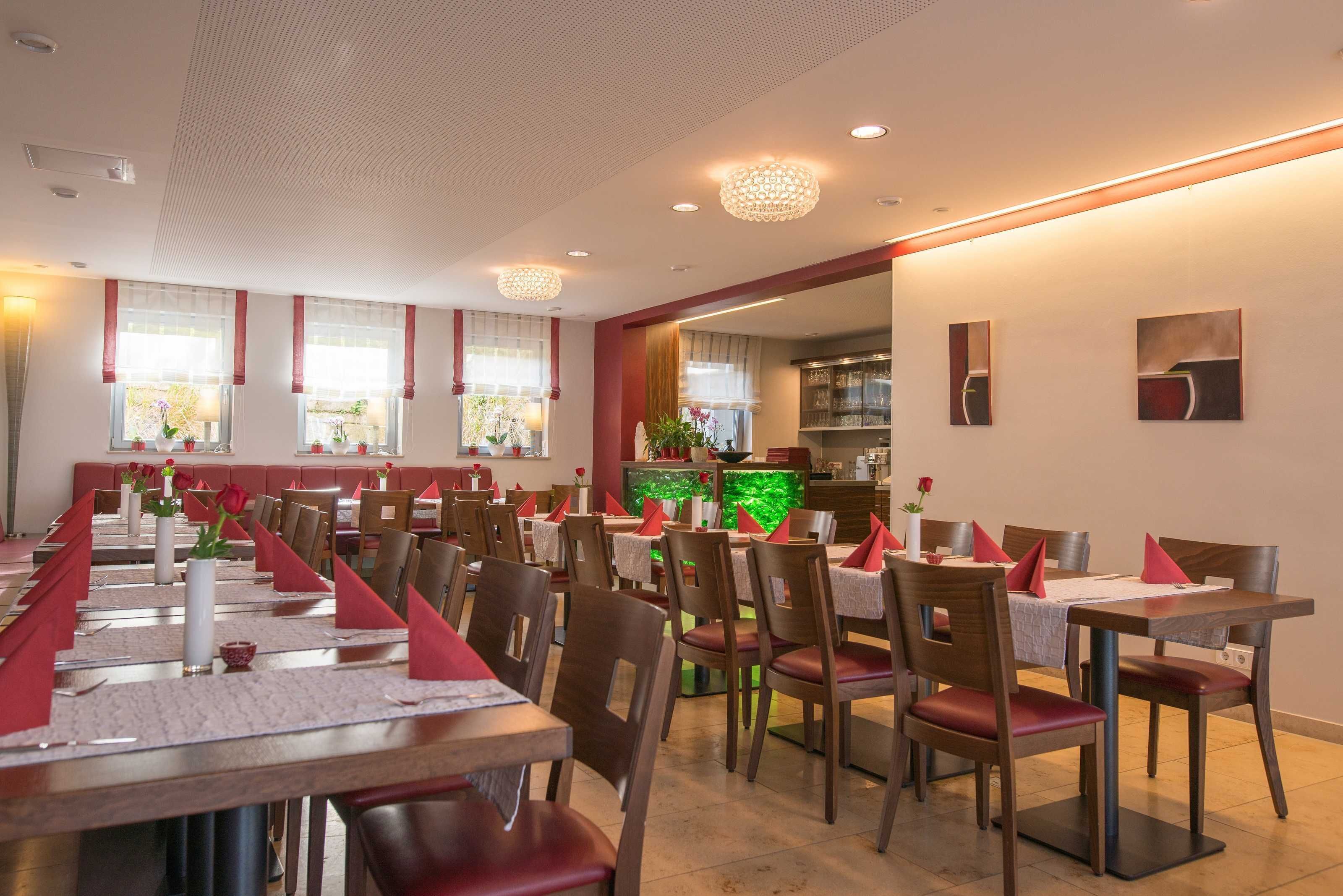 A restaurant with long tables, red napkins, and wooden chairs.