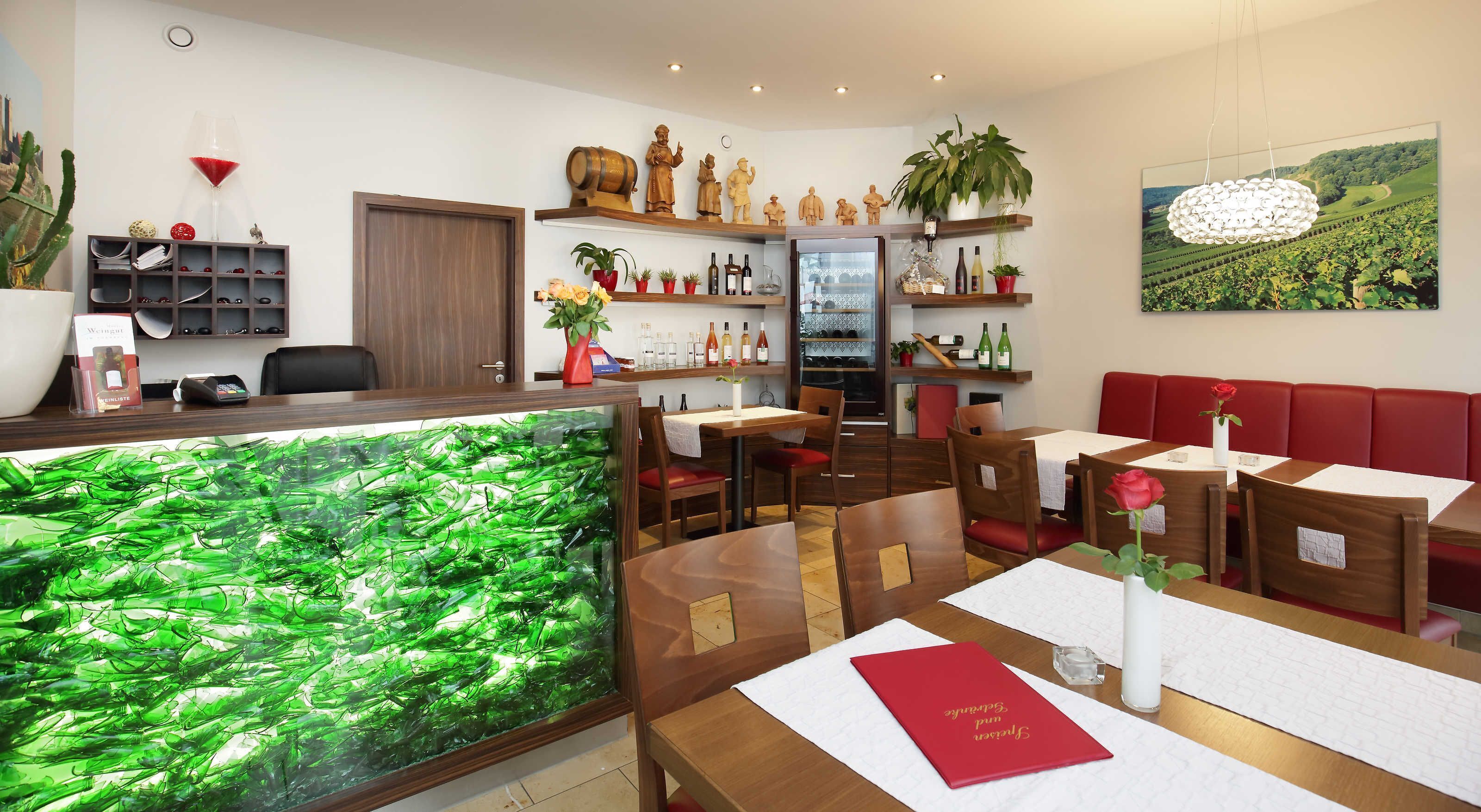 Ein Restaurantinneres mit Holztischen, einem großen Aquarium und Weinflaschen auf Regalen.