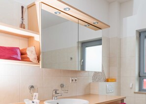 Ein modernes Badezimmer mit einem großen Spiegel, einem Waschbecken und einem Fenster.