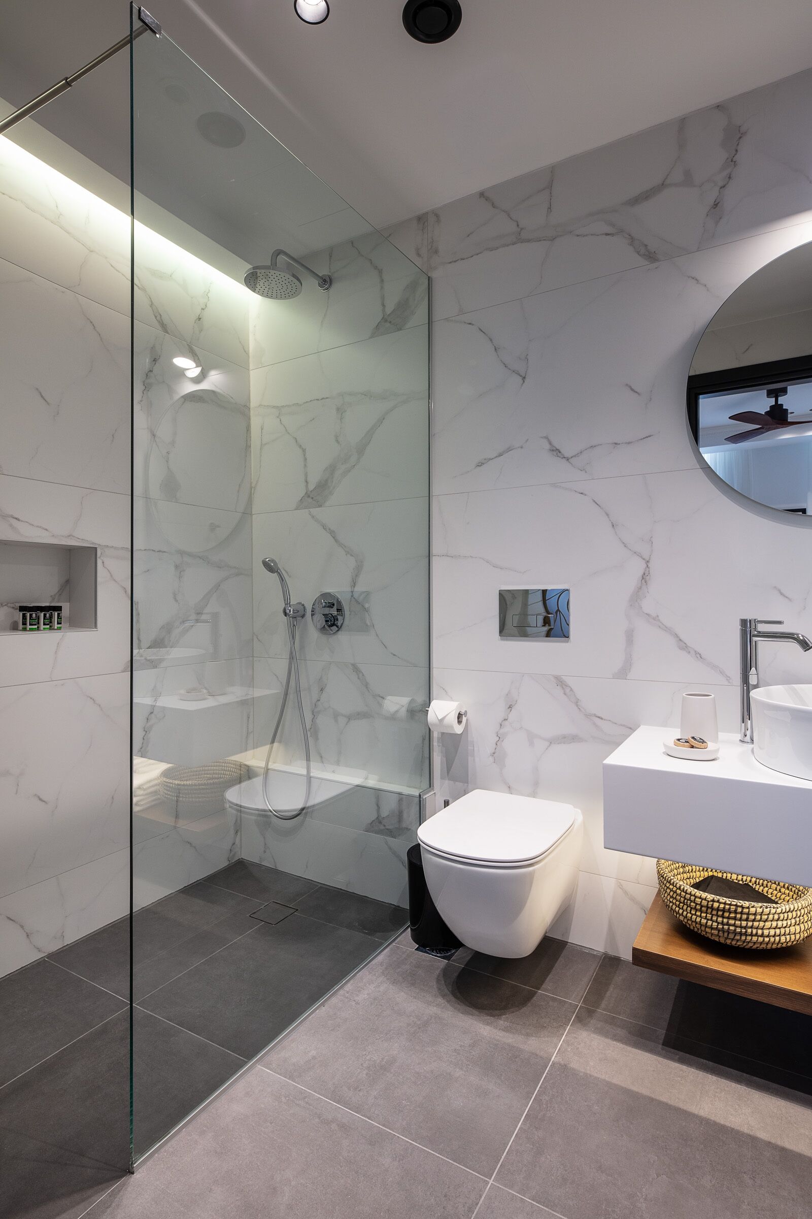 Un bagno moderno con doccia vetrata, un water bianco e un mobile lavabo con lavandino e specchio.