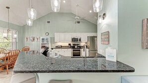 Una cocina con encimeras de granito, armarios blancos y electrodomésticos de acero inoxidable.