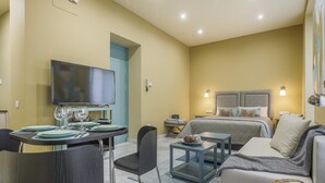 Een moderne hotelkamer met een bed, een bank, een eettafel, stoelen en een televisie.