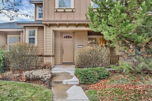 Stroll up to the front door, surrounded by lush gardens and a beautiful evergreen tree.