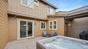 A backyard with a hot tub, string lights, and a patio area with chairs and a table. - Tranquility On The Bluffs 3 Bedroom Townhouse by RedAwning (Bend)