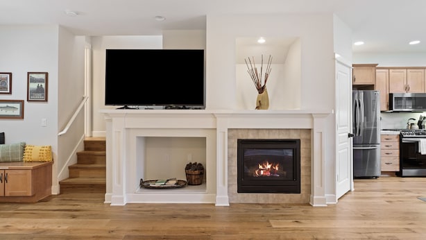 A modern living room with a fireplace, a flat-screen TV, and a staircase leading to another level. - Tranquility On The Bluffs 3 Bedroom Townhouse by RedAwning (Bend)