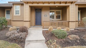 A two-story building with a front porch, a dark blue door, and a small sign above the door. - Tranquility On The Bluffs 3 Bedroom Townhouse by RedAwning (Bend)