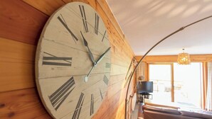 A large wall clock with Roman numerals in a wooden interior.