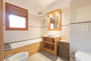 Een bad/douchecombinatie, een haardroger, een bidet, handdoeken