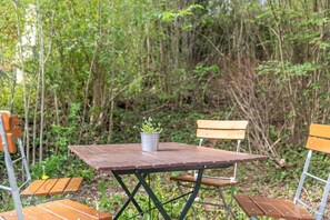 Ein Holztisch mit Metallstühlen, umgeben von viel Grün.