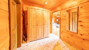 A wooden interior with a large wardrobe, a tiled floor, and a door leading to another room. - Vacation home Frankenglück - Apartment Holz vor der Hütt'n (Egloffstein)