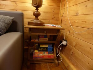Ein Interieur einer Holzhütte mit einer Couch, einem Bücherregal aus Holz und einer Steckdose.