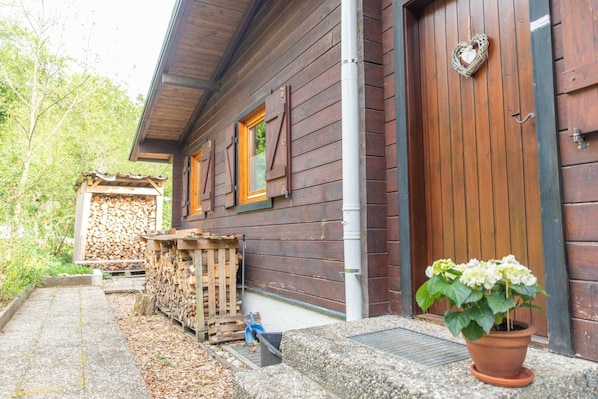 A wooden cabin with a door, windows, and a potted plant.