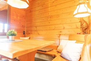 A wooden cabin interior with a wooden table, bench seating, and a decorative horse sculpture. - Frankenglück Vacation Home - Holz vor der Hütt'n Apartment (Egloffstein)
