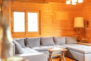 L'intérieur d'un chalet en bois, avec un canapé, une table et une lampe.