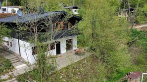 Une maison à deux étages, dotée d’une antenne parabolique, d’un petit porche et d’un escalier en pierre.