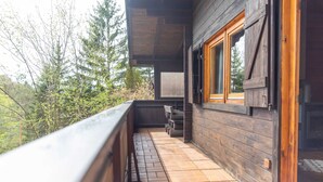 A wooden balcony with a tiled floor, a wooden railing, and a window with a wooden frame. - Vacation home Frankenglück - Apartment Holz vor der Hütt'n (Egloffstein)