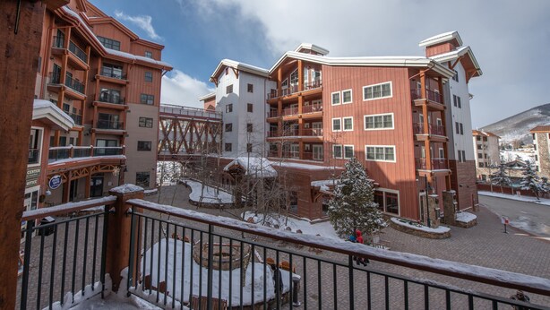 Um hotel com vários andares, varandas e um pátio coberto de neve.