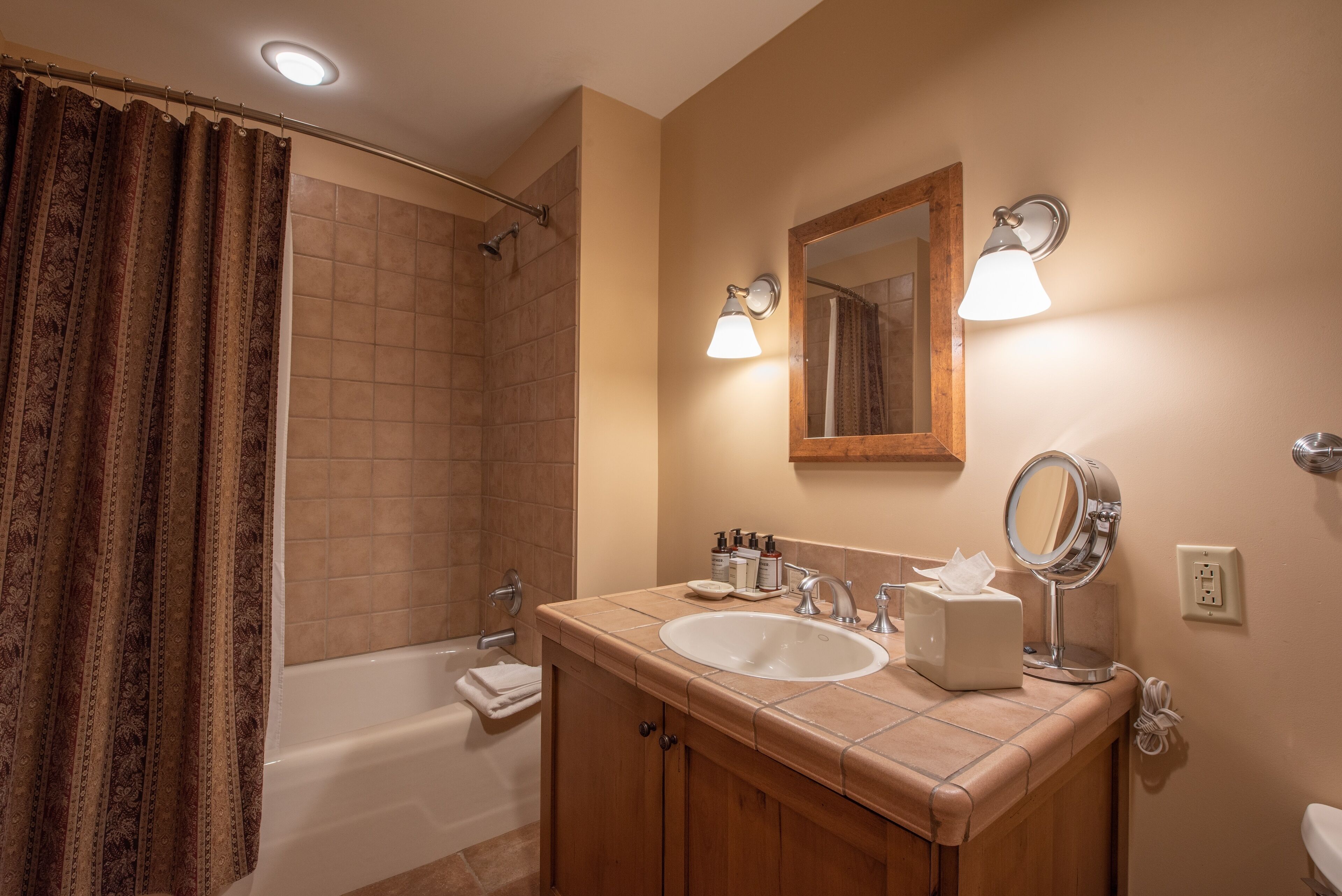 Un bagno con una vasca, un lavabo, uno specchio e una tenda da doccia.