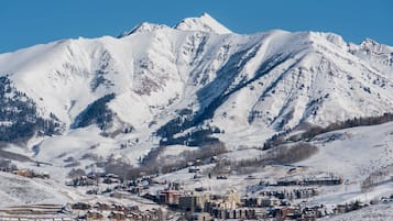 Un pueblo cubierto de nieve en la montaña, con edificios y un pico prominente al fondo.