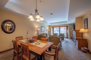 A dining area with a wooden table and chairs, a chandelier, and a mirror on the wall. - Spacious 2 Bedroom Unit In Mountaineer Square Condo - No Cleaning Fee! by RedAwning (Crested Butte)
