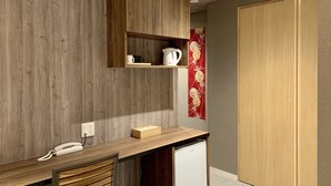 A compact room with a wooden desk, a chair, a small white refrigerator, and a wooden wardrobe. - Asakusa Kaminarimon Takenoyado (Tokyo)