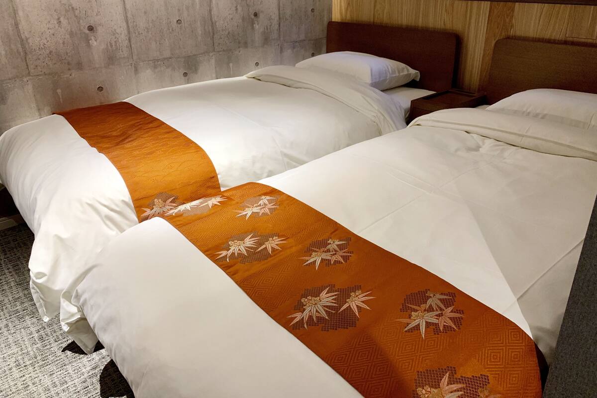 Two beds with white bedding and orange decorative pillows.