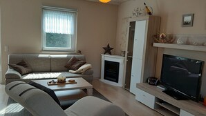 Una sala de estar moderna con un sofá gris, una mesa de centro de madera, un televisor de pantalla plana y una chimenea.