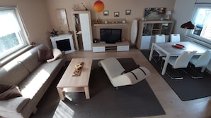 Una sala de estar moderna con sofá, mesa de centro, televisor y zona de comedor.