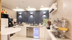 Une cuisine moderne équipée d’une machine à café intégrée, d’un réfrigérateur et d’un distributeur de jus.