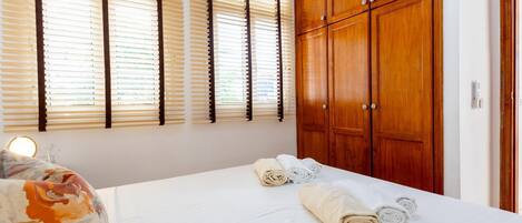 Une chambre d’hôtel avec un lit, une armoire en bois et une fenêtre avec des stores.