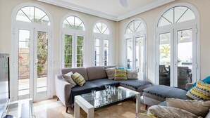 Ein geräumiges Wohnzimmer mit einem Glastisch, einem grauen Sofa und einem Deckenventilator.