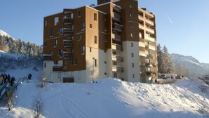 A multi-story building with a modern architectural style, located in a snowy mountainous area. - Studio for 3, slopeside in Les Adrets (Les Adrets-Prapoutel)