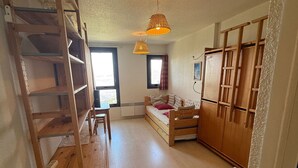 A compact room with a bunk bed, a desk, a chair, a wardrobe, and a hanging light fixture. - Studio for 3, slopeside in Les Adrets (Les Adrets-Prapoutel)