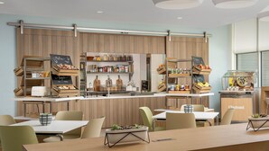 Um café moderno com interior de madeira, prateleiras abertas com petiscos e um balcão com máquina de café.