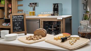 A kitchen counter with a loaf of bread, cheese, and a cutting board with cheese and a knife. There is a sign indicating 'Time to Relax' and a coffee machine.