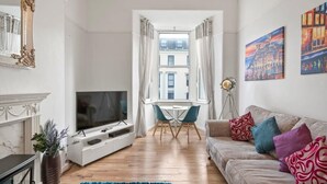 Ein Wohnzimmer mit Fernseher, einer Couch und Kunstwerken.
