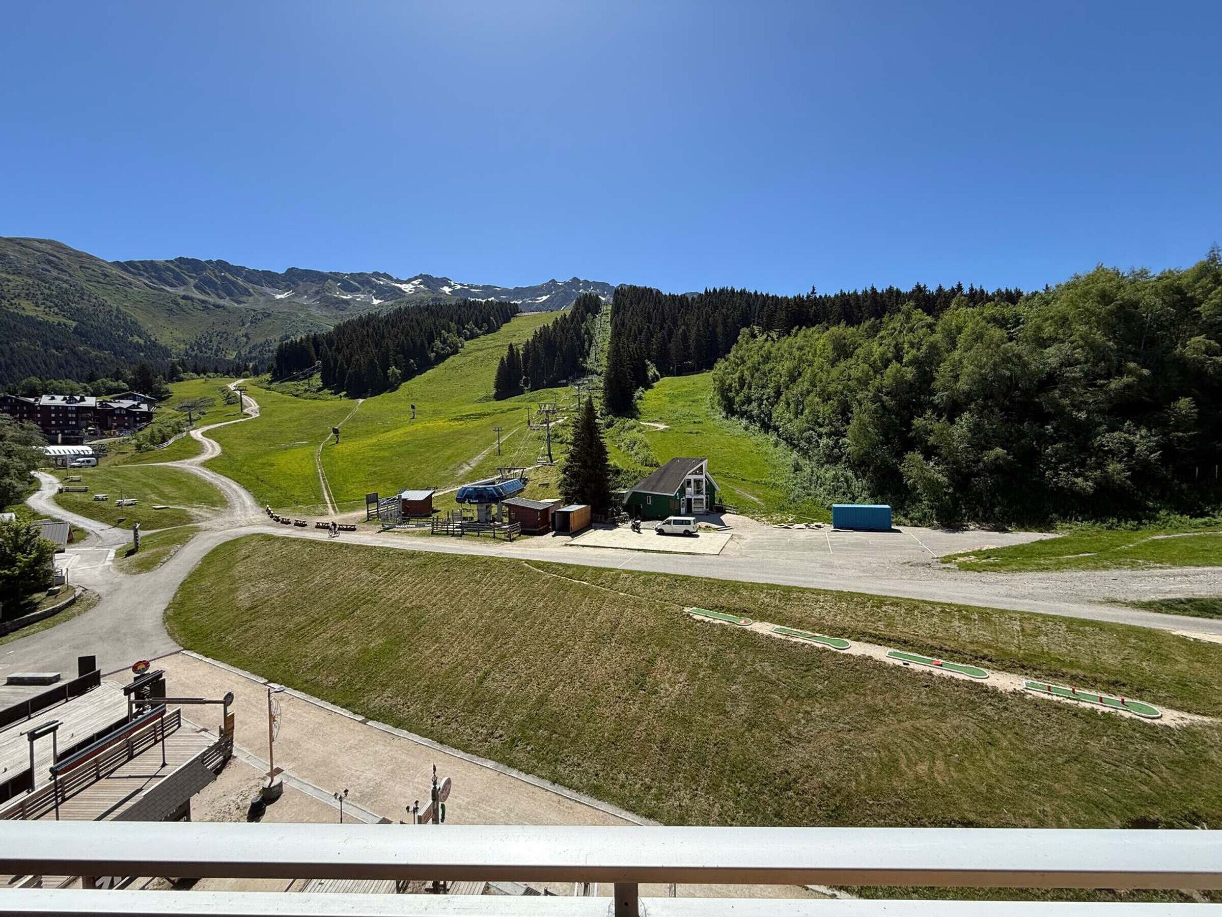 A mountain resort with a ski lift, a small lodge, and a parking area.